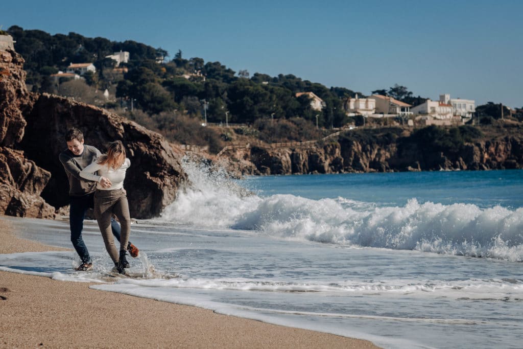 Un couple joue avec les vagues sur la plage